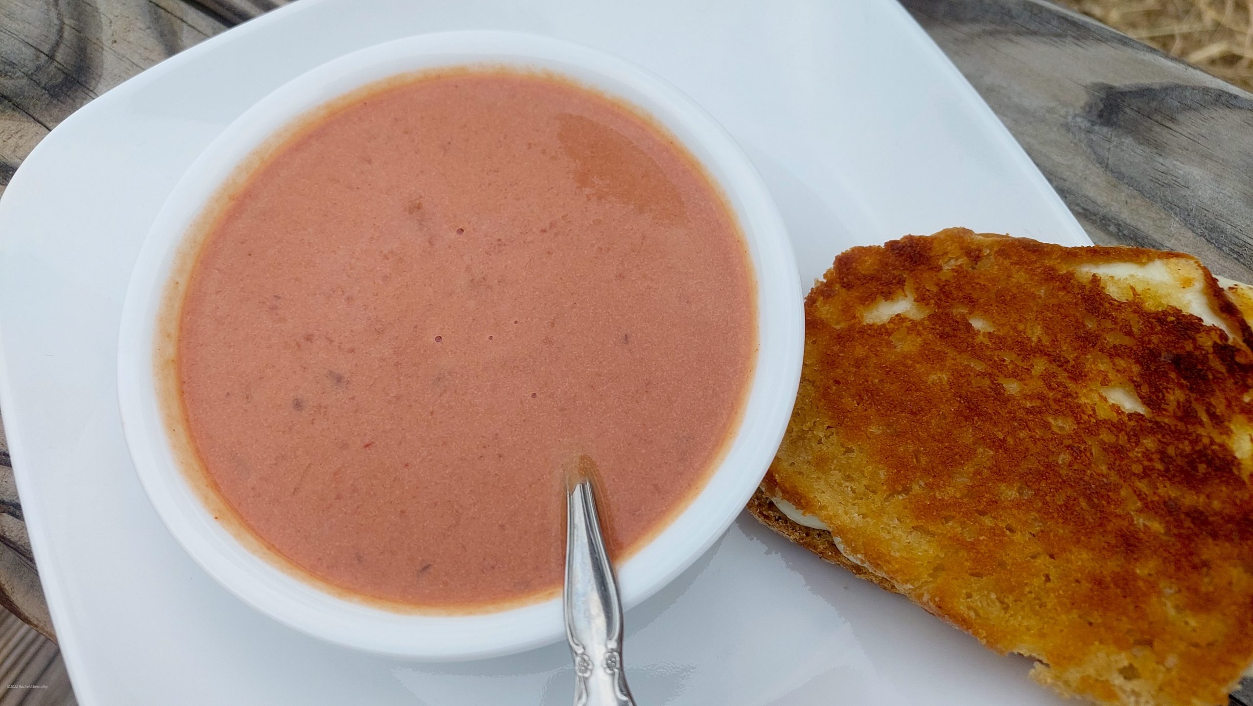 A creamy bowl of tomato soup with a grilled cheese sandwich on the side.
