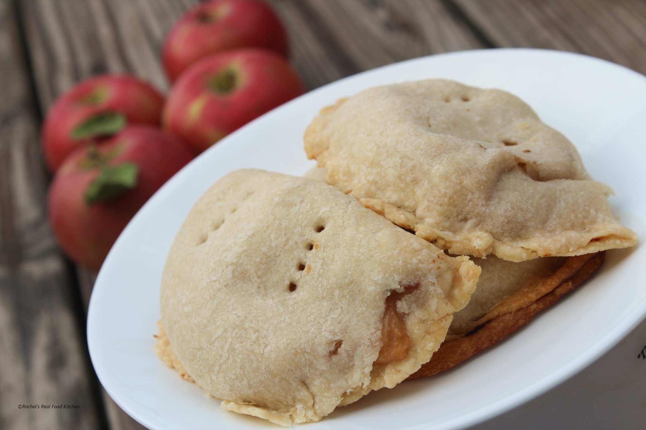 No-sugar apple turnovers on a plate in front of several red apples.